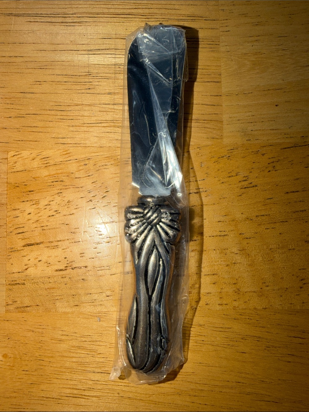 cheese knife with a distinct decorative bow or ribbon design on the handle